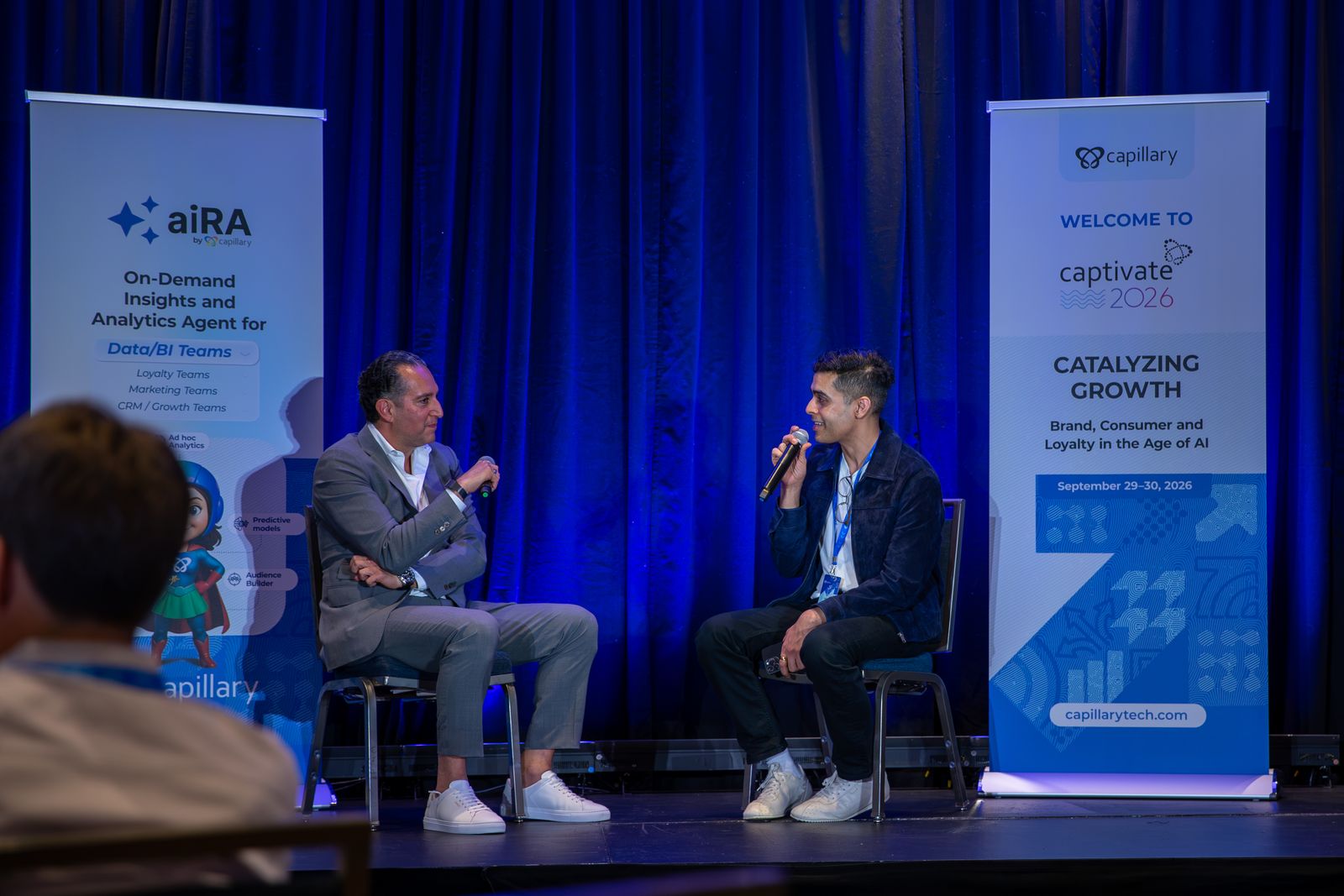 A fireside chat on the Captivate 2026 stage, between an aiRA banner and the Catalyzing Growth welcome banner